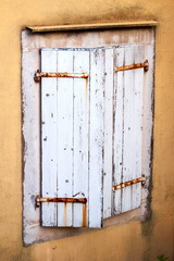 old wooden white window shutters on the old yellow wall of the historic city house