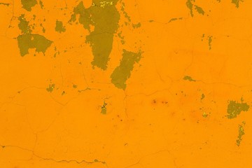 Old wall covered with yellow paint with cracks