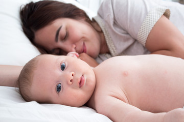 Baby and mom. A brunette woman lies with a blond child. Top view