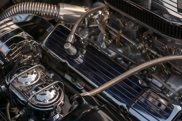 Engine Compartment of a Classic Luxury Car with lots of Chrome Parts Close-Up.