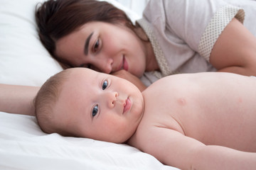 Baby and mom. A brunette woman lies with a blond child. Top view