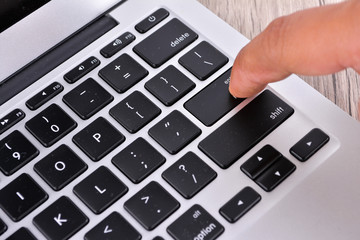 Hand touching laptop computer keyboard - Focus on the keyboard