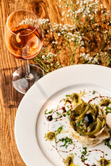 Beautiful cod dish viewed from above with glass of wine.