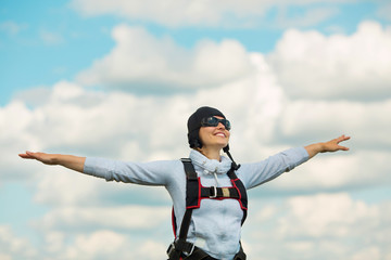 beautiful young woman in parachuting gear against the sky with clouds