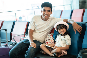 happiness father and daughter smiling while look at the camera in the airport waiting room