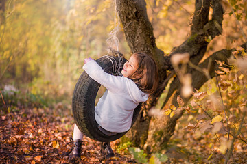 little girl swinging on a rubber wheel from a car