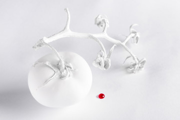 Conceptual photo: white tomato and red drop on a white background. Selective focus 