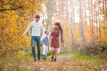 Mom, Dad and Daughter are walking in the autumn forest