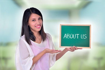 Young Women holding chalkboard with text About Us