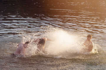 Adult men splashing in the water. People play in water. Silhouettes of men playing in the pond.