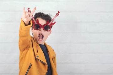child with sunglasses doing rock symbol with hands up