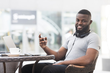 Happy african american guy sitting cafe with free wifi