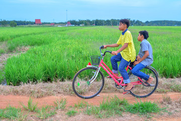 Obraz premium happy young local boy riding old bicycle at paddy field