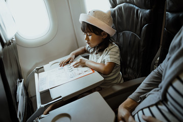 Fototapeta premium Asian little girls are busy reading while sitting in the aircraft cabin