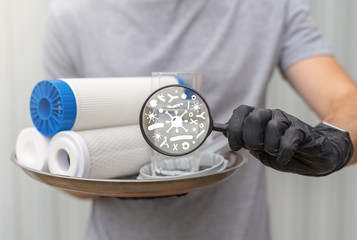 Service man hold water filtering cartridges with glass and spanner installation and magnifying...