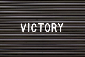 Black color felt letter board with white alphabet in word victory background