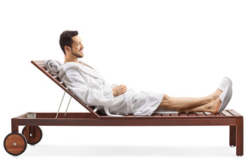 Young man in a bathrobe relaxing on a lounge chair