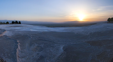 Obraz premium Turkey, sunset on the travertine terraces at Pamukkale (Cotton Castle), natural site of sedimentary rock deposited by water from the hot springs, famous for a carbonate mineral left by flowing water