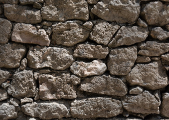Grey stone wall texture with bright sunlight. Closeup