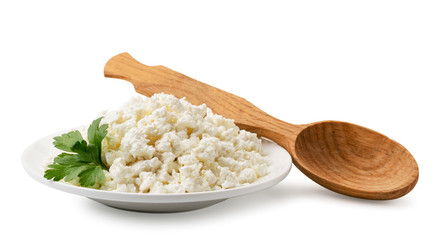 Cottage cheese with parsley leaf in a plate and a wooden spoon on a white background. Isolated.