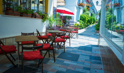 Summer streets, Holidays, Empty tables, Resort, Sun terraces for tourists in summer in Marbella, Malaga, Spain