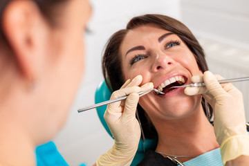 Putting dental braces to the woman's teeth at the dental office. Dentist examine female patient with braces in dental office. Close-up of a young attractive girl with braces on the teeth