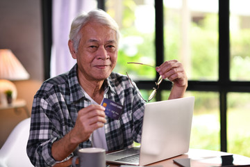 Asian senior man using credit card for online shopping