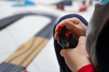 MANO DI UN BAMBINO CHE REGGE IL JOYSTICK DELLA PISTA DELLE MACCHINE TELECOMANDATE