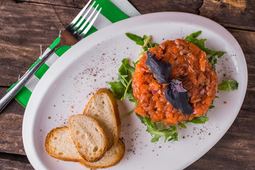 Salmon tartare with arugula and croutons rustic table