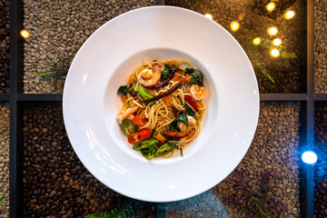 Spaghetti with spicy prawn in white dish on coffee beans table