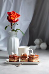 Layered cakes with rose on a white marmorean table.
