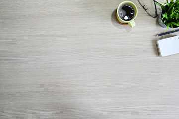 Workspace with notepad, coffee, glasses and plant on wood table top view.