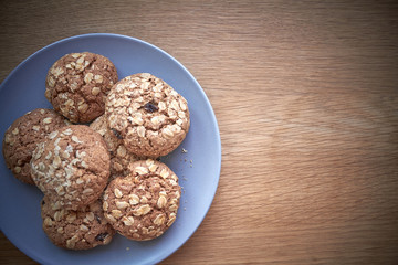 Top view of a few oatmeal cookies on a gray plate on a light wooden surface, selective focus