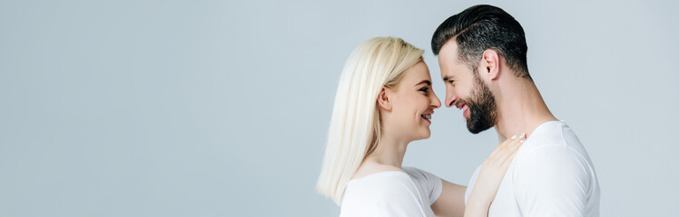 panoramic shot of beautiful smiling young couple embracing isolated on grey