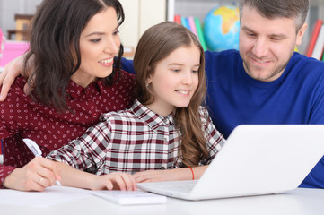 parents and daughter using laptop in room