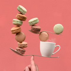 Balancing cup of coffee and macaronos on a finger