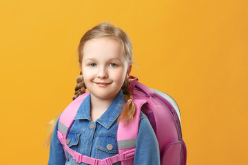 Portrait of a little girl schoolgirl with a backpack on a yellow background. Back to school. The concept of education. Copy space.