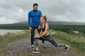 Male coach training woman outdoors on gloomy day