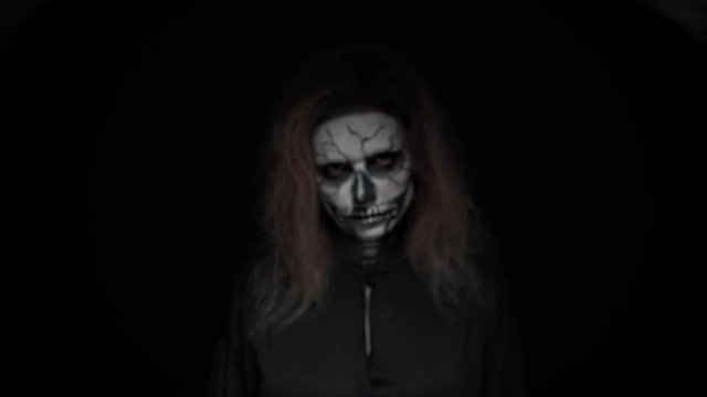 concept, beautiful makeup for halloween. Portrait of a young sexy girl with skull makeup. on a black background, face in the dark. close-up
