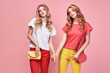 Fashionable embracing woman smiling on pink background. Two Shapely Girl sisters Having Fun dance,...