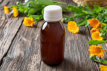 A bottle of calendula tincture with blooming calendula
