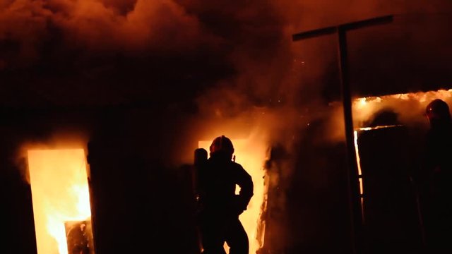 Rescue service, firefighters eliminate the flames of a wooden house fire. Real arson of the building.
