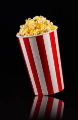 Paper striped bucket with popcorn isolated on black background