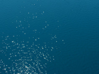 Bright small sunny sparkling highlights on the bright blue deep water surface of the lake background.