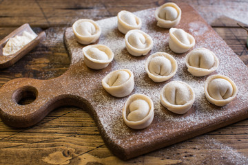 Raw Russian traditional dumplings on wooden background