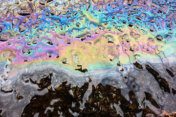 A leaked Car Oil Petrol in The Rain on a Tarmac Road Metallic Rainbow