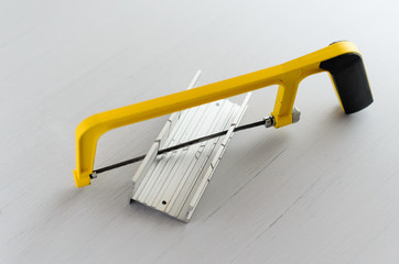 yellow hand saw and aluminium miter box for hobby in home workshop