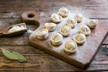 Raw Russian traditional dumplings on wooden background