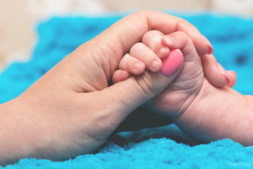 Mom and baby hold hands together on a blue background.