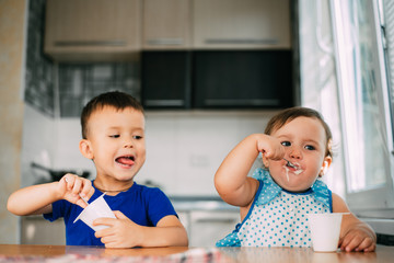 Boy and Girl in the kitchen eating yogurt on a warm summer day